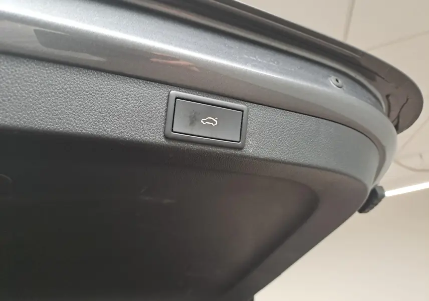 Gros plan sur le bouton d'ouverture électrique du coffre, intégré dans le hayon gris graphite d'une Skoda Octavia Combi 2024.