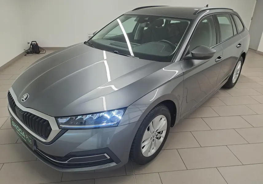 Vue 3/4 avant droite d'une Skoda Octavia Combi 2024 gris graphite métallisé avec phares allumés en intérieur.