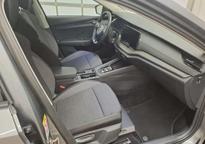Vue intérieure côté conducteur de la Skoda Octavia Combi 2024, sièges tissu gris et tableau de bord moderne noir.