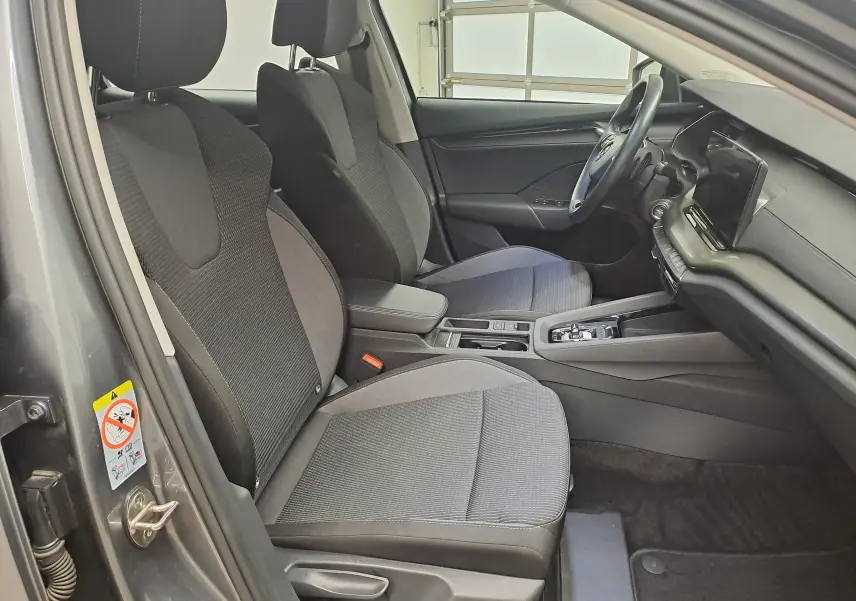 Intérieur avant de la Skoda Octavia Combi 2024 gris graphite, vue côté conducteur avec sièges tissu et tableau de bord moderne.