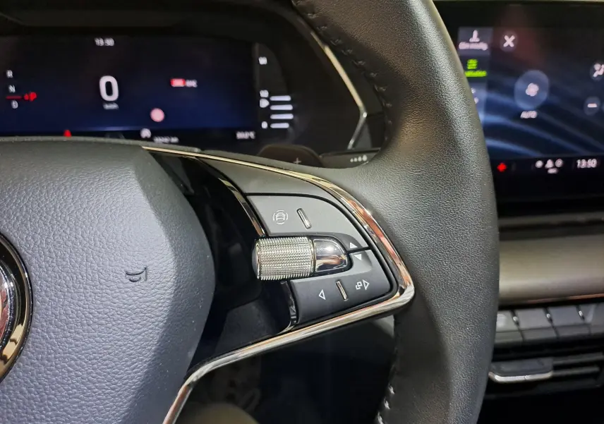 Gros plan sur la partie droite du volant en cuir noir de la Skoda Octavia Combi 2024 avec commandes et molette chromée.