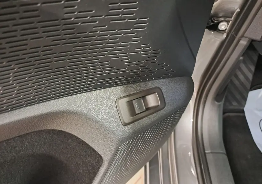 Gros plan sur le bouton d'ouverture électrique du coffre dans l'habitacle gris graphite d'une Skoda Octavia Combi 2024.