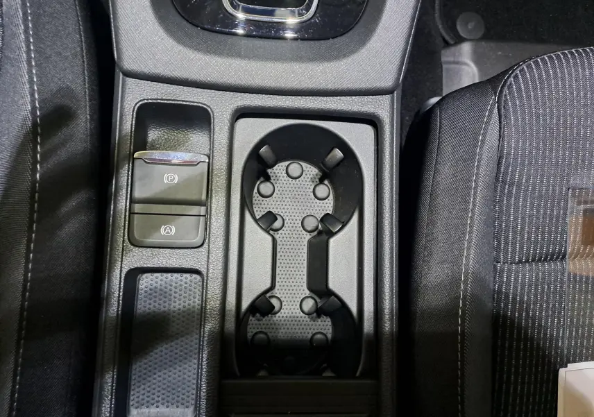 Gros plan sur la console centrale de la Skoda Octavia Combi 2024, avec porte-gobelets et boutons de frein à main électrique en noir.