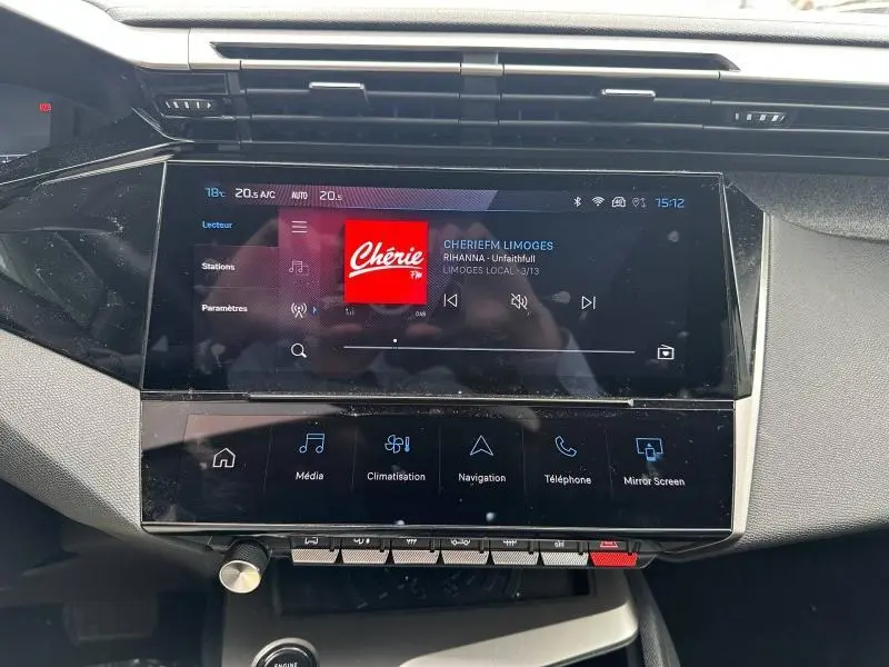 Écran tactile central du tableau de bord de la Peugeot 308 blanc Okénite, affichant la radio Chérie FM.