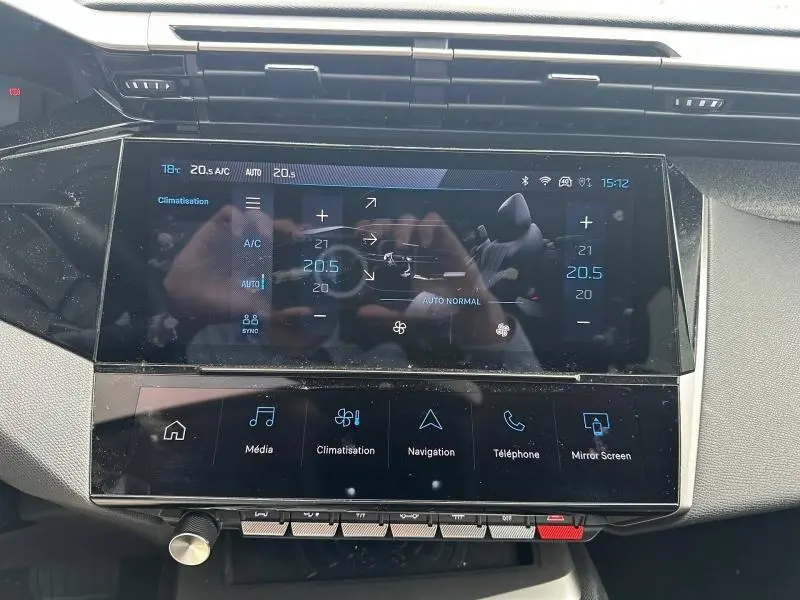 Vue rapprochée de l'écran tactile central du tableau de bord de la Peugeot 308 Hybrid blanc Okénite, affichant la climatisation.