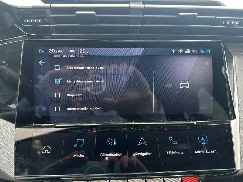 Gros plan sur l'écran tactile central du tableau de bord de la Peugeot 308 blanche, affichant les options d'alerte de conduite.