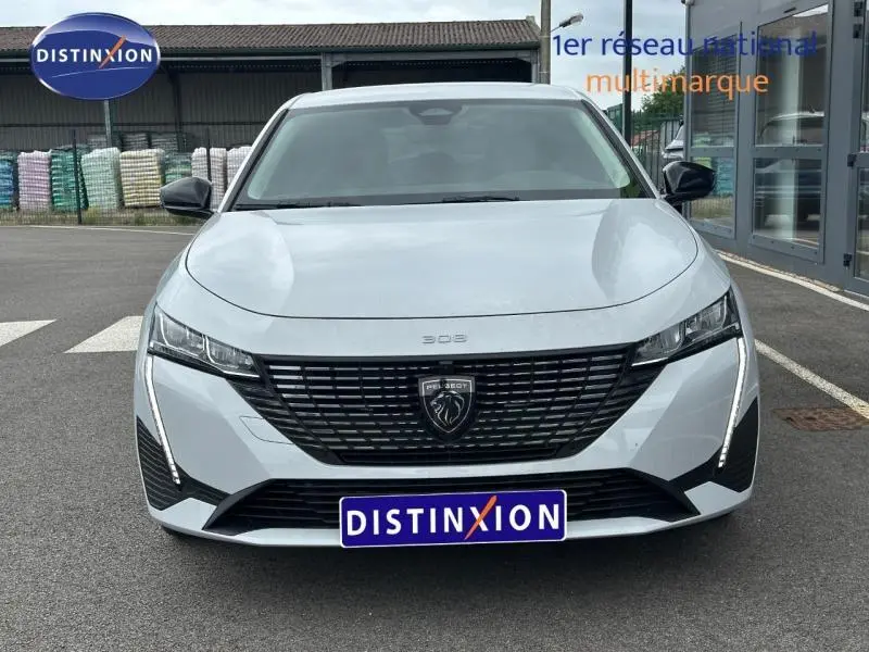 Vue avant d'une Peugeot 308 blanche Okénite avec calandre noire et feux LED verticaux distinctifs.