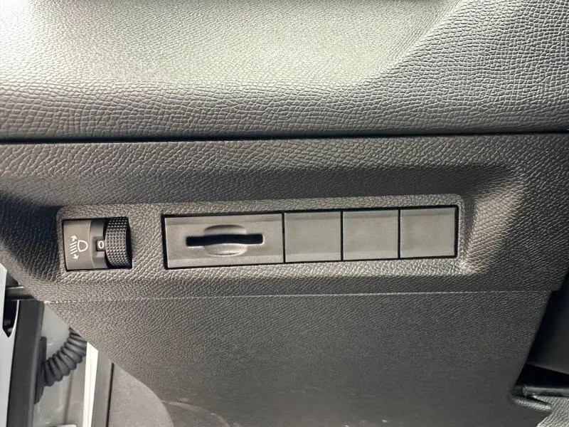 Vue rapprochée des commandes de réglage des phares et de l'intensité lumineuse sur le côté gauche du tableau de bord noir.