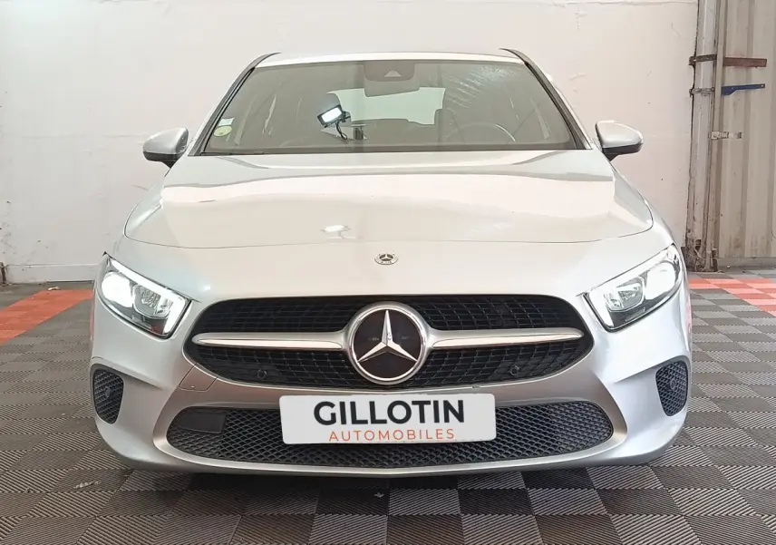 Vue frontale d'une Mercedes Classe A 180 d Business Line gris clair avec phares LED allumés et calandre distinctive.