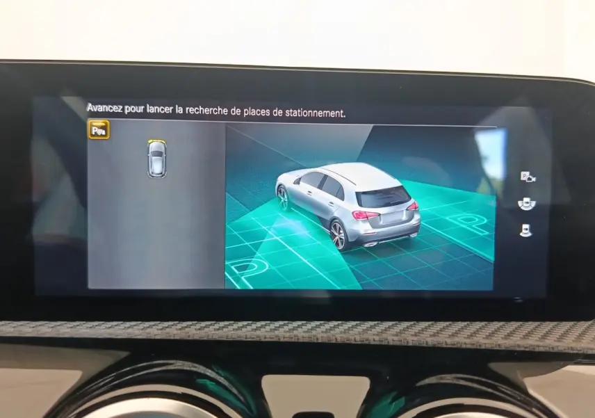 Affichage tactile intérieur montrant la recherche de place de stationnement d'une Mercedes Classe A gris clair vue en 3/4 arrière.