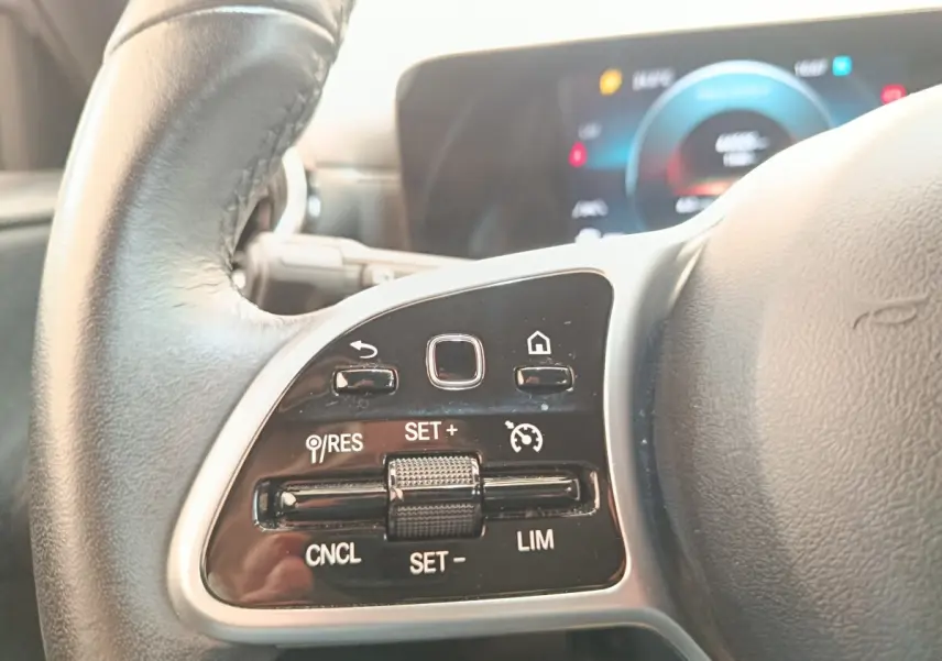 Gros plan sur le volant cuir noir de la Mercedes Classe A 180 d Business Line avec commandes multifonctions côté gauche.
