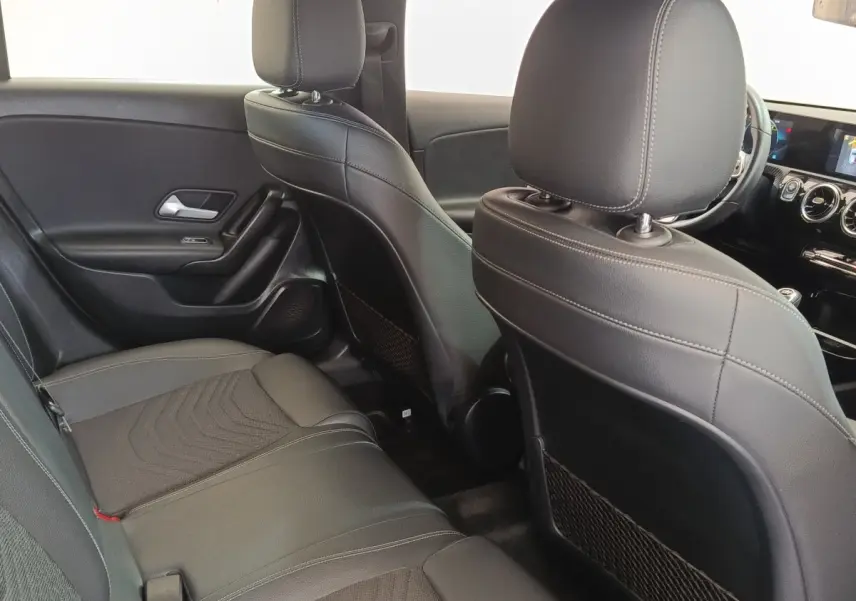 Vue intérieure arrière droite de la Mercedes Classe A 180 d Business Line avec sièges en cuir noir et tableau de bord visible.