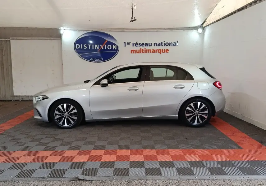 Vue de profil côté gauche d'une Mercedes Classe A 180 d Business Line gris clair dans un showroom.