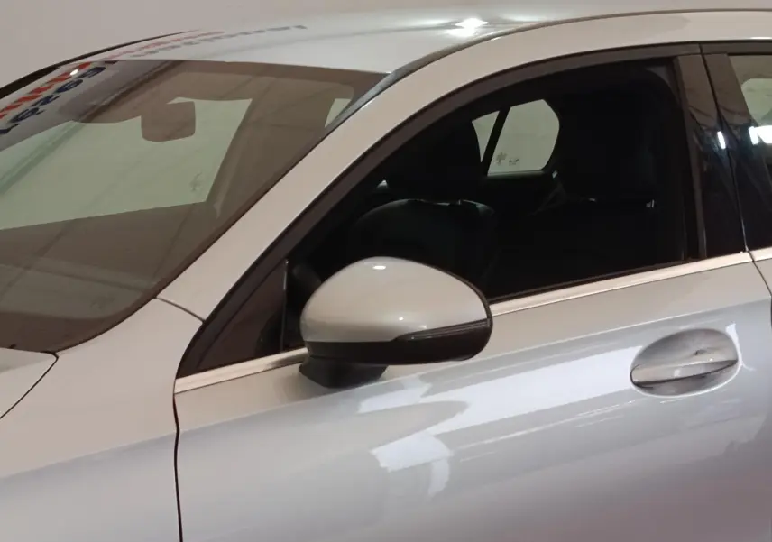 Vue latérale côté gauche d'une Mercedes Classe A 180 d Business Line gris clair avec rétroviseur et poignée de porte visibles.
