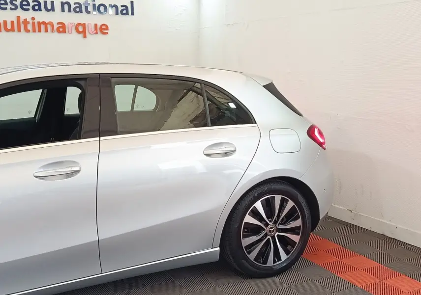 Vue côté droit arrière d'une Mercedes Classe A gris clair avec jantes alliage distinctives et feux arrière allumés.