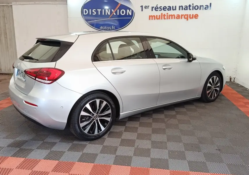 Vue 3/4 arrière droite d'une Mercedes Classe A 180 d Business Line gris clair, avec jantes alliage et feux LED distinctifs.