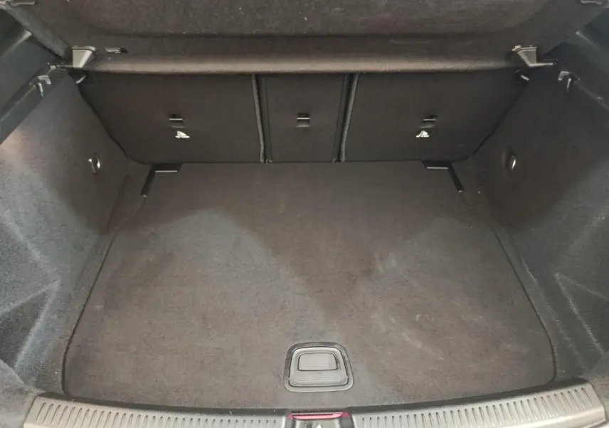 Vue plongeante sur le coffre spacieux et vide d'une Mercedes Classe A gris clair, avec banquette arrière rabattable.