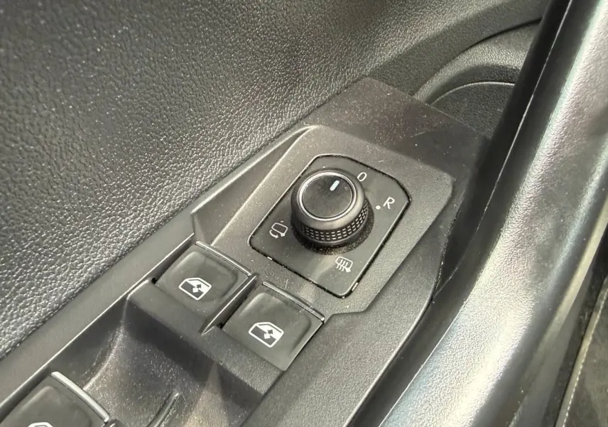 Gros plan sur les commandes de réglage des rétroviseurs et des vitres côté conducteur du Volkswagen Taigo gris.