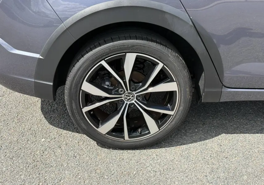 Gros plan sur la roue arrière droite du Volkswagen Taigo gris, avec jante alliage noire et argentée au design R-Line.