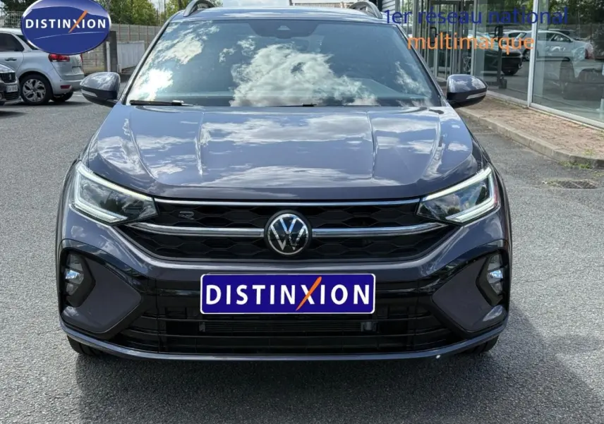 Vue avant d'un Volkswagen Taigo gris Ascot 2025 avec calandre noire et phares LED allumés.