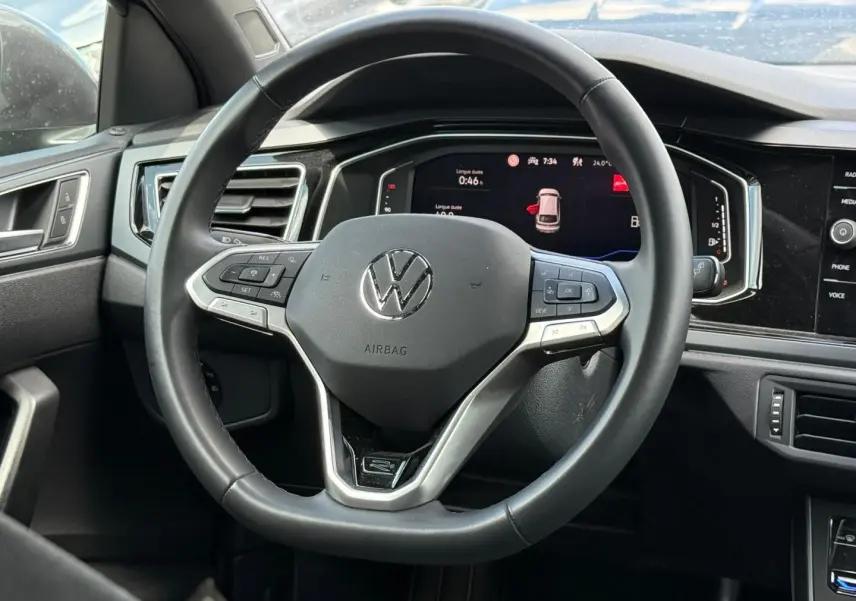 Vue rapprochée du volant cuir multifonction noir du Volkswagen Taigo 1.0 TSI 116ch R-Line avec tableau de bord numérique.