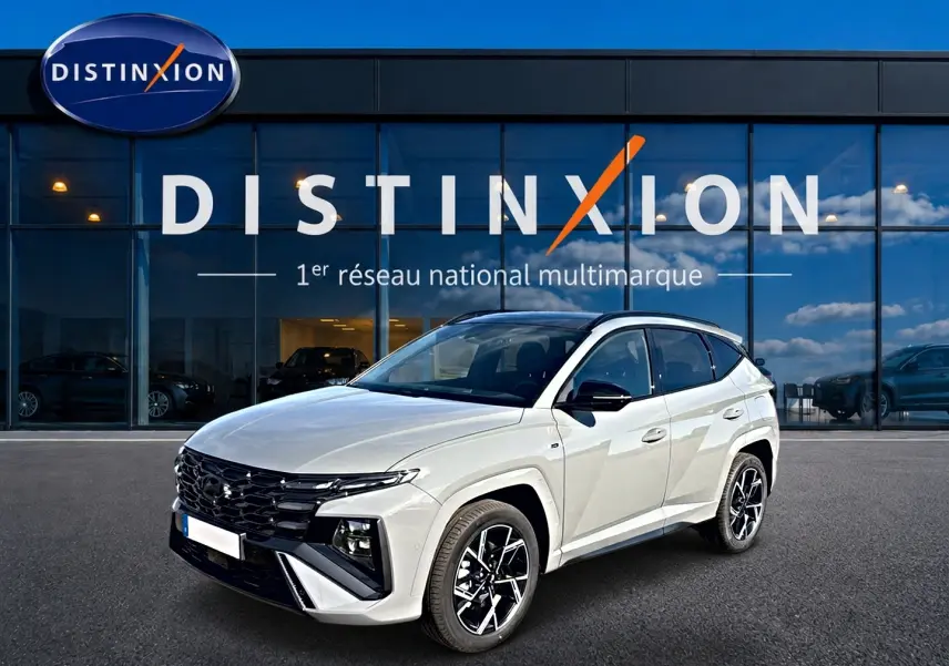 Hyundai Tucson 2026 blanc en 3/4 avant droit avec calandre noire et jantes alliage devant showroom Distinxion.