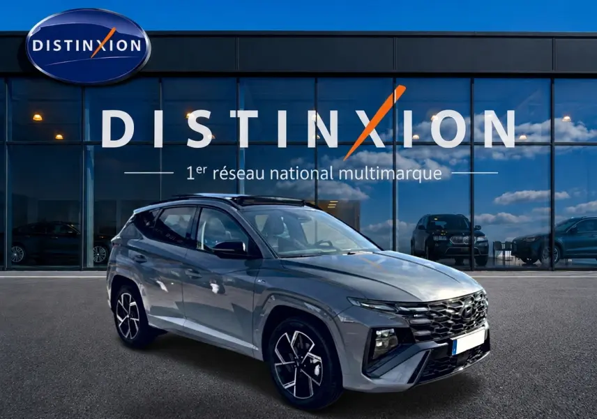 Hyundai Tucson 2026 gris shadow en 3/4 avant droit, avec calandre chromée et jantes alu distinctives.