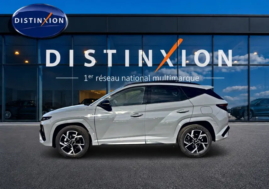Hyundai Tucson 2026 gris shadow en profil droit devant vitrine Distinxion, jantes alu noires et toit noir.