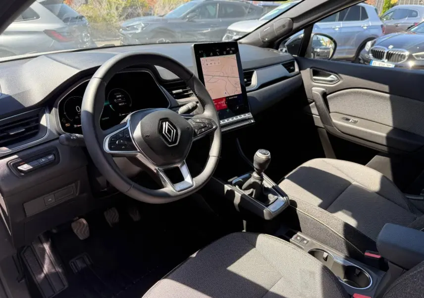 Vue intérieure côté conducteur du Renault Captur 2025 avec tableau de bord noir et écran tactile vertical.