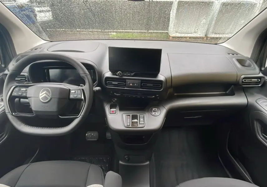 Intérieur du Citroën Berlingo 2025 vue de face, tableau de bord noir avec écran tactile central et volant multifonction.