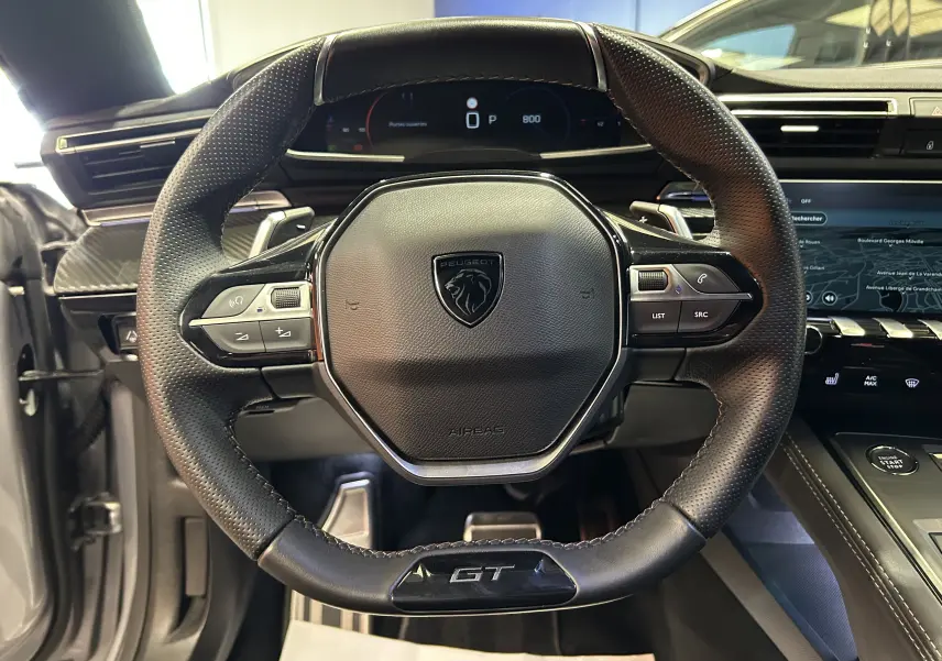 Volant cuir GT de la Peugeot 508 SW 2024, vue frontale centrée sur les commandes et le tableau de bord digital.