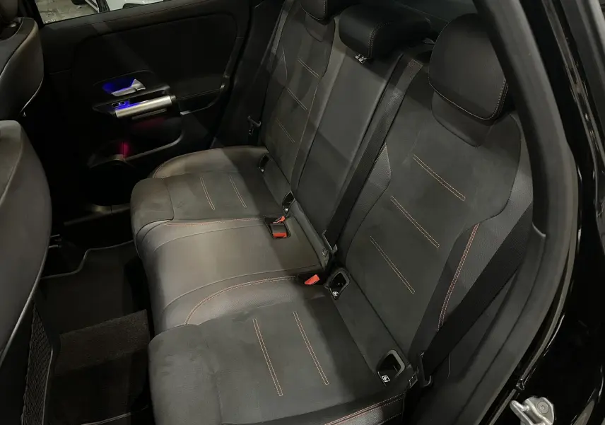 Vue intérieure arrière droite des sièges noirs avec surpiqûres rouges du Mercedes GLA 250E AMG Line 2023 en Noir Cosmos.