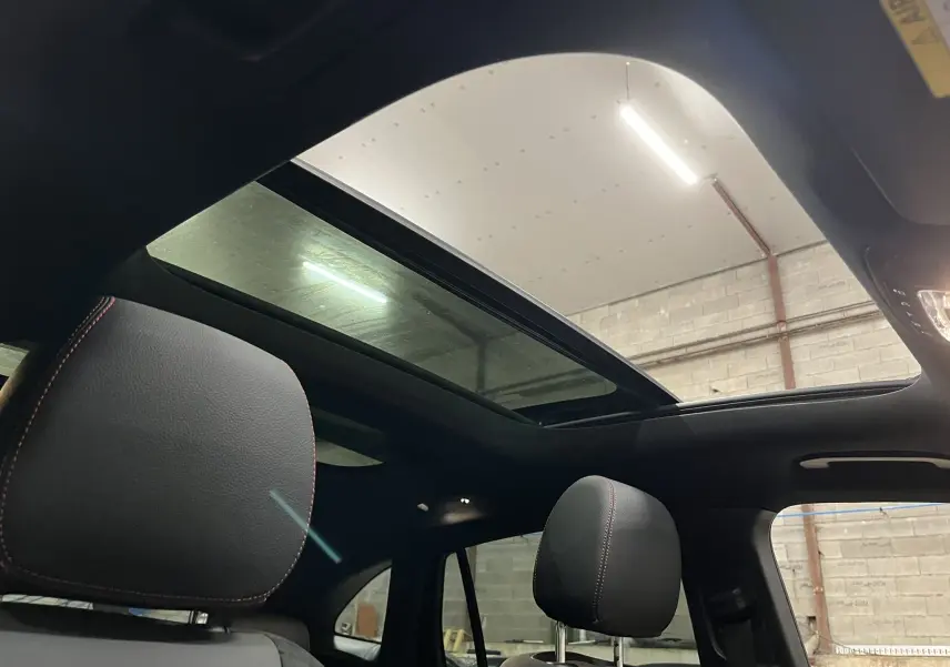 Vue intérieure du toit ouvrant panoramique et des appuie-têtes noirs avec surpiqûres rouges du Mercedes GLA 250E AMG Line 2023.
