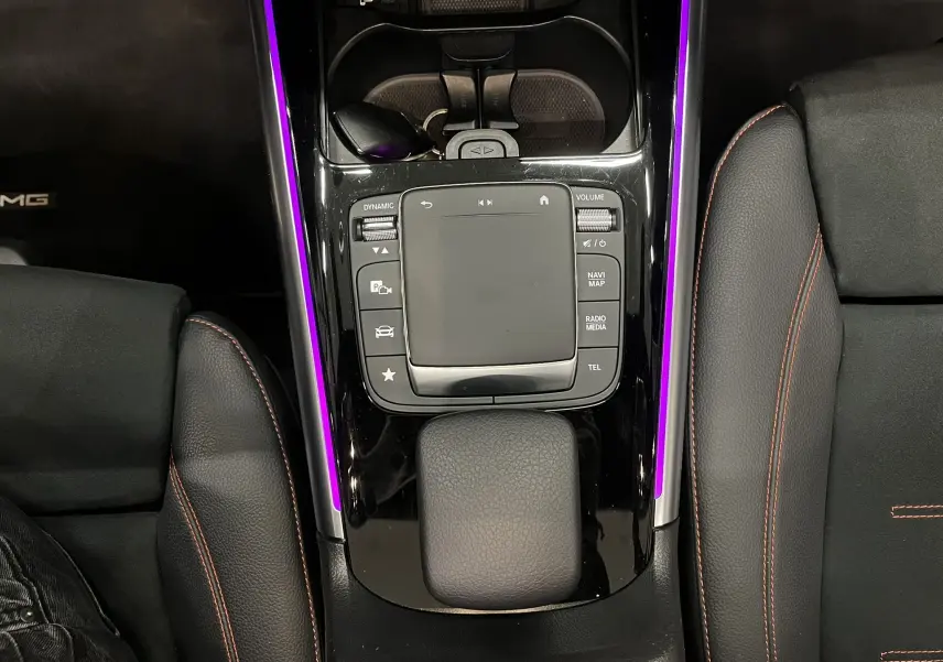 Vue plongeante sur la console centrale noire du Mercedes GLA 250E AMG Line avec éclairage d'ambiance violet et surpiqûres rouges.