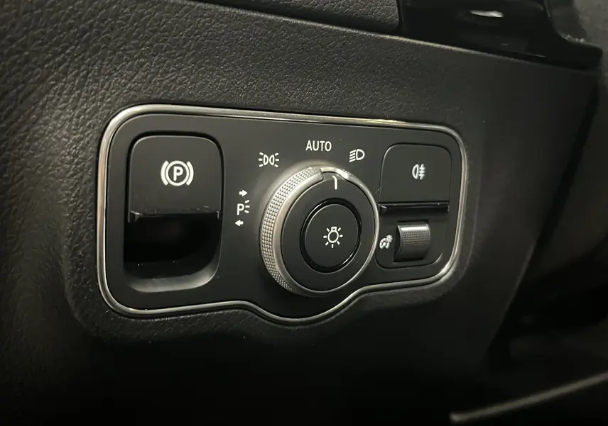 Gros plan sur la commande d’éclairage et frein de stationnement dans l’habitacle noir du Mercedes GLA 250E AMG Line 2023.