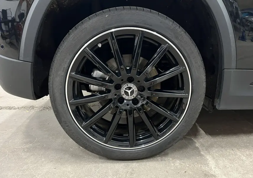 Gros plan sur la roue avant gauche noire brillante avec jante AMG à multiples branches du Mercedes GLA 250E AMG Line 2023.