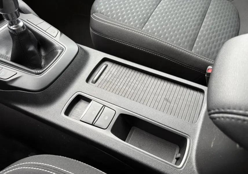 Gros plan sur la console centrale noire du Ford Kuga 2024 avec boîte manuelle et siège avant tissu gris.