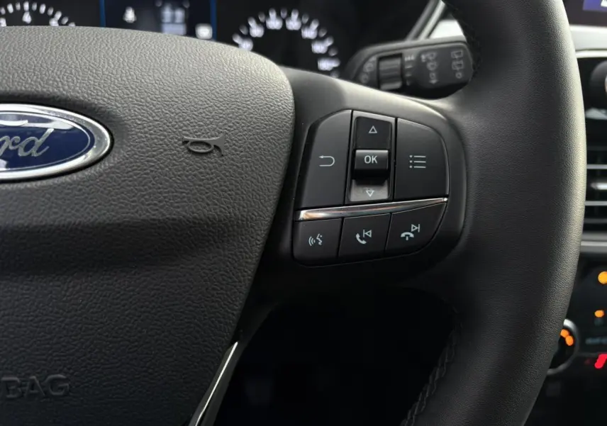 Gros plan sur le volant multifonctions en cuir du Ford Kuga 2024, avec commandes audio et téléphone intégrées.