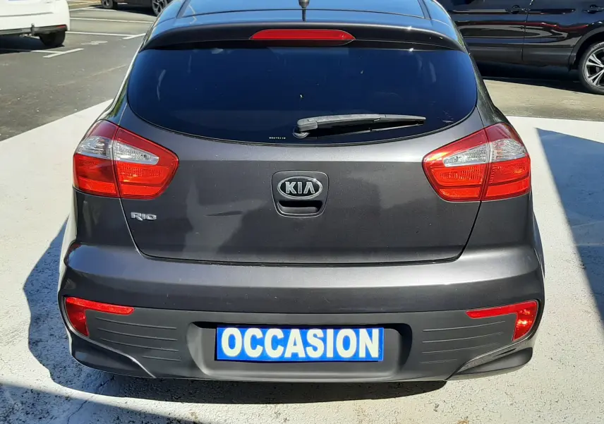 Vue arrière d'une KIA Rio grise 5 portes de 2016 avec feux rouges et plaque "OCCASION" visible.