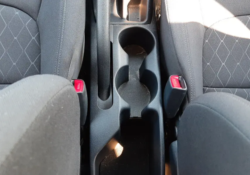 Vue plongeante sur la console centrale noire entre les sièges tissu gris d'une KIA Rio 1.2 85CH ACTIVE 5 portes de 2016.