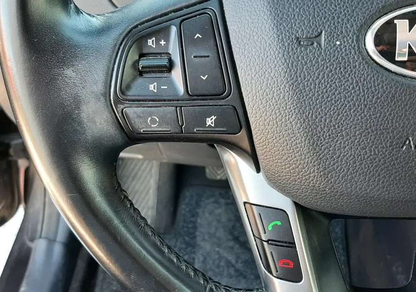 Gros plan sur le volant noir de la KIA Rio 2016, avec commandes audio et téléphone intégrées visibles côté gauche.
