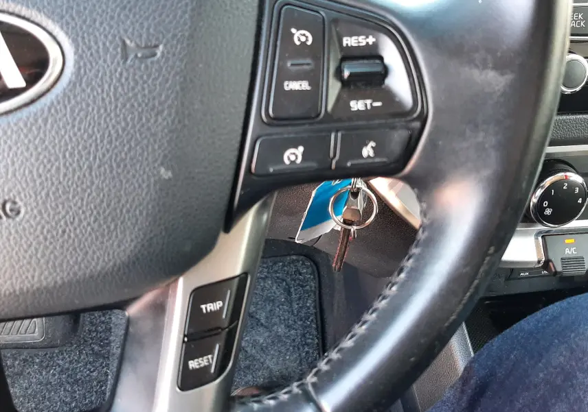 Gros plan sur le volant noir de la Kia Rio 2016, avec commandes de régulateur de vitesse et clés insérées à droite.