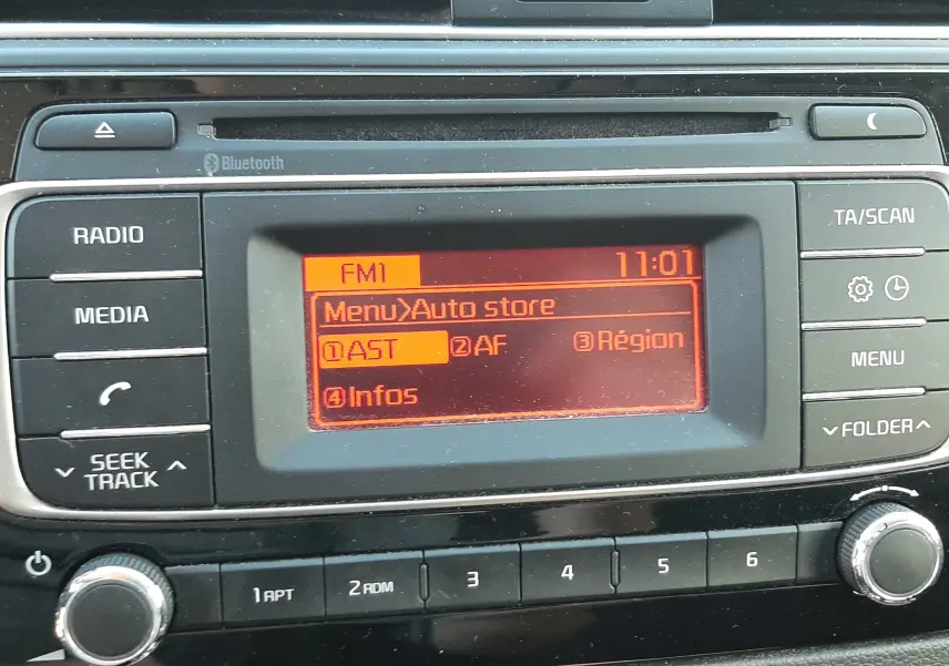 Vue rapprochée de la console centrale de la Kia Rio grise 2016, affichant l'écran radio FM avec menu Auto store.