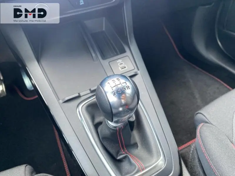 Gros plan sur le levier de vitesses manuel chromé avec surpiqûres rouges dans l'habitacle noir du Ford Puma.