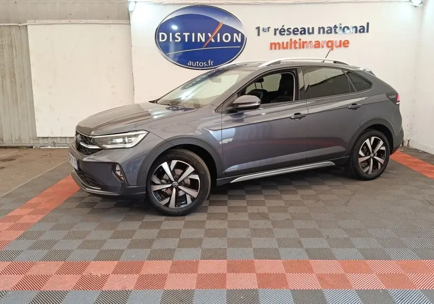 Vue de profil côté gauche du Volkswagen Taigo gris foncé 2023 avec jantes alliage et vitres teintées en showroom.