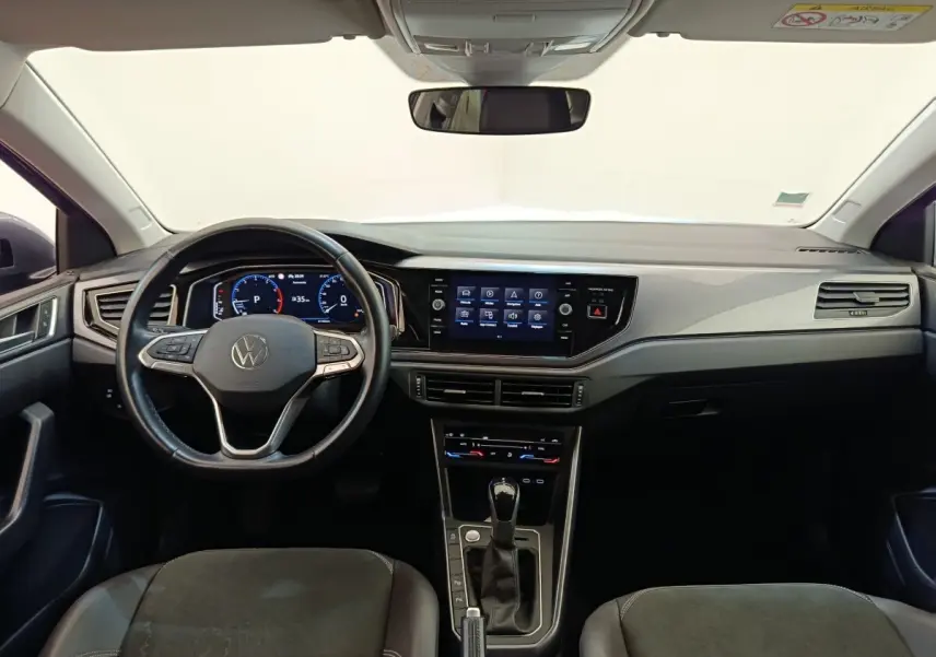 Vue intérieure frontale du tableau de bord et volant cuir noir du Volkswagen Taigo 2023, avec écran tactile central allumé.