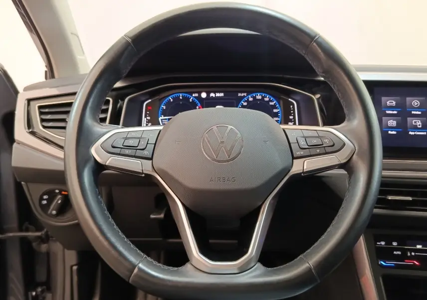 Vue rapprochée du volant en cuir noir du Volkswagen Taigo 1.5 TSI 150 DSG Style avec tableau de bord numérique allumé.