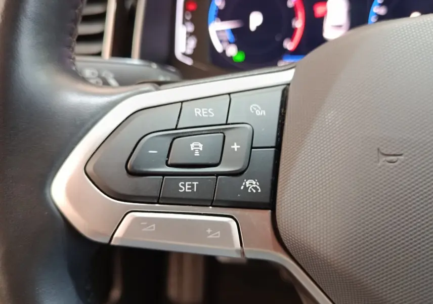 Gros plan sur les commandes de régulateur de vitesse au volant cuir alu du Volkswagen Taigo gris foncé 2023.
