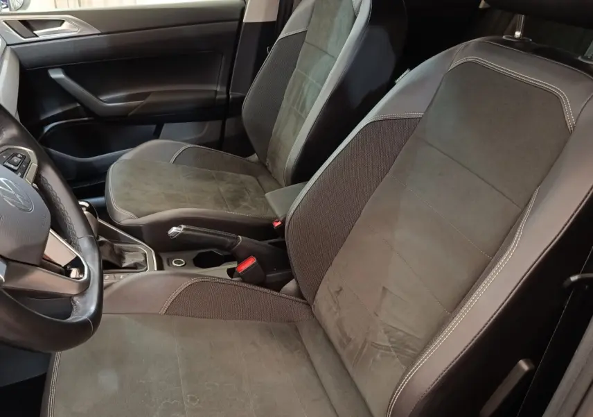 Vue intérieure côté conducteur du Volkswagen Taigo 2023, sièges tissu gris foncé avec surpiqûres claires.