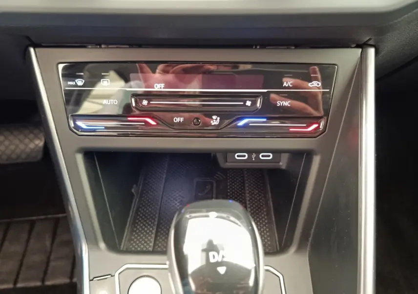 Vue rapprochée de la console centrale du Volkswagen Taigo 2023, avec commandes climatisation et levier de boîte auto brillant.